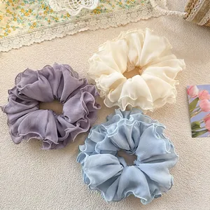 Three oversized chiffon hair scrunchies in cream, lavender and sky blue on a floral base