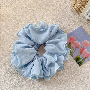 Detailed view of light blue ruffled scrunchie with soft chiffon texture and wavy layers
