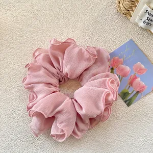 Detail of light pink pleated hair scrunchie with wavy edges on cozy textured background
