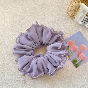 Close-up of lilac ruffled chiffon hair scrunchie with delicate hem and layered pleats