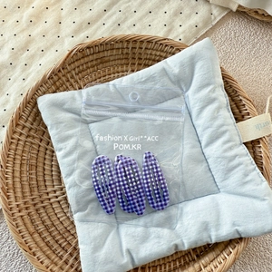 Gros plan de pinces à cheveux à carreaux violets présentées dans un sachet scellé