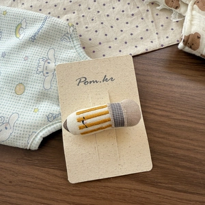 Detail of handmade fabric hair clip in pencil shape with delicate embroidery and texture