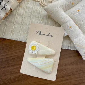 Détail de pinces à cheveux marguerite en dentelle sur tissu jaune pour filles