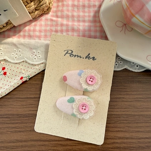 Detail von rosa Stoff-Haarclips mit süßen Drucken und zarten Spitzenblumen-Akzenten