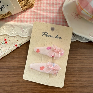 Detail von rosa Stoff-Haarspangen mit Herzmuster und Organza-Schleifen auf Karte