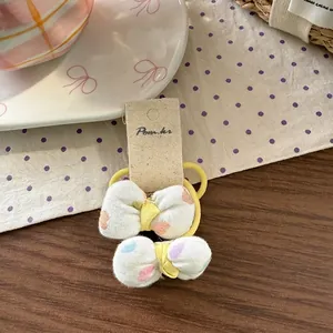 Detail view of two fabric bow hair ties with colorful polka dots on a wooden background