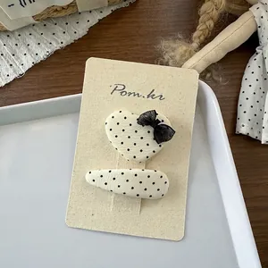 Detail van beige haarspeldjes met stippen en een zwarte mesh strik op kaart