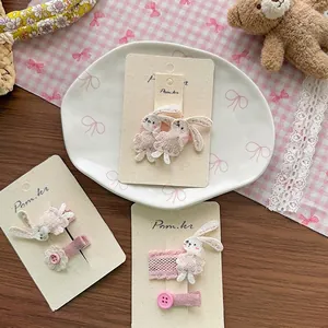 Süßes rosa besticktes Kaninchen-Haarclip-Set mit Blumenakzenten auf Gitterhintergrund