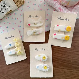 Detail of four pairs of floral lace hair clips and ribbon bows on beige cardstock