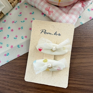 Detail of fabric bow hair clips with colorful heart patterns and gold ring accents