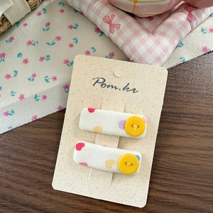 Close-up of fabric hair clips with polka dots, heart patterns and yellow buttons