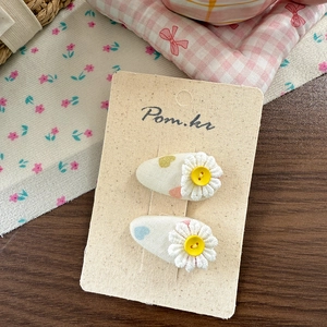 Detail of fabric hair clips with daisy flower and button on beige card display