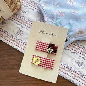 Détail de barrettes à cheveux à carreaux rouges avec motif Mickey et bouton
