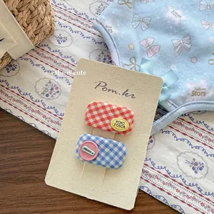 Détail de pinces à cheveux en tissu à carreaux rouges et bleus avec badges mignons
