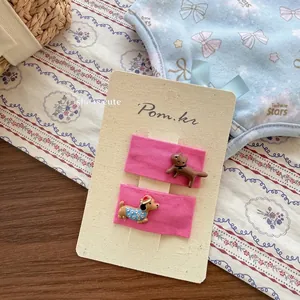Détail de barrettes en tissu rose avec de mignons ornements de chiots en résine 3D