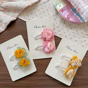 Close-up of chiffon fabric flower hair clips with pearls and lace on card base