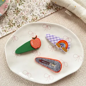Detail of handmade embroidered fruit and rainbow hair clips with secure felt-covered backing