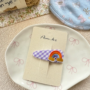 Close-up of cute purple plaid hair clip with colorful embroidered rainbow and clouds