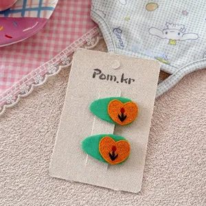 Detail von bestickten grünen Haarklammern mit Tulpen und Herzen auf einer beigen Karte