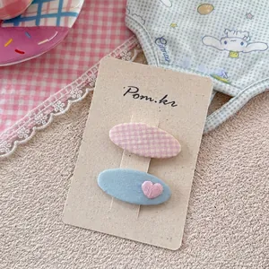 Detailansicht der Haarspangen mit rosa Karomuster und blauem Herz-Stickmotiv