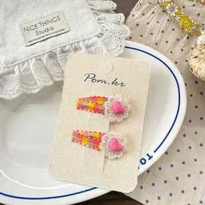 Détail de pinces à cheveux avec dentelle florale et tissu à carreaux orange pour filles