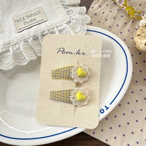 Détail de pinces à cheveux pour enfants avec dentelle florale et motif à carreaux