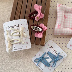 Blue denim and cream silk bow hair clips set with pearls on display card