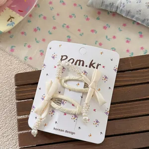 Detail of cream fabric bow hair clips with white pearls on a display card