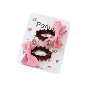 Set of two pink fabric bow hair clips with gold metal plates and brown pom-poms