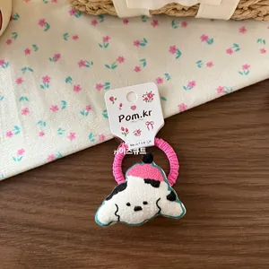 Détail de l'élastique à cheveux avec broderie chien rose sur fond en bois esthétique