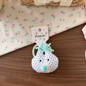 Détail d'un chouchou en tissu à pois avec nœud vert menthe sur carte de présentation