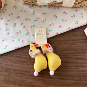 Vue détaillée de chouchous canards jaunes en peluche avec nœud en tulle rose et élastique