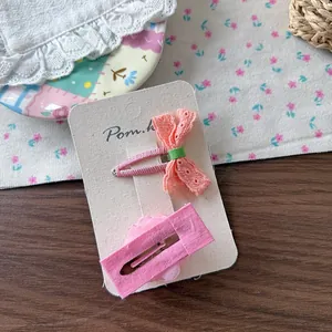 Detail of pink lace bow hairpin and floral fabric clip on branded display card