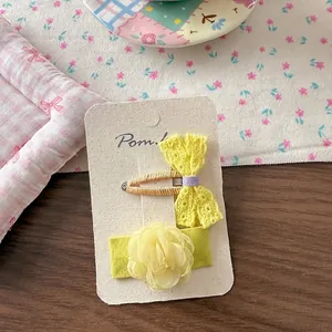 Detail of yellow lace bow and mesh flower hair clip set on display card