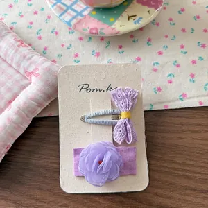 Detail of purple lace bow and layered mesh flower hair clips on a display card