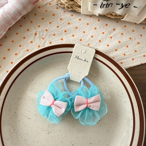 Detail of light blue mesh flower hair ties with pink bows on a white card