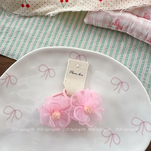 Gros plan de deux élastiques à fleurs en tulle rose avec centres en peluche sur plateau