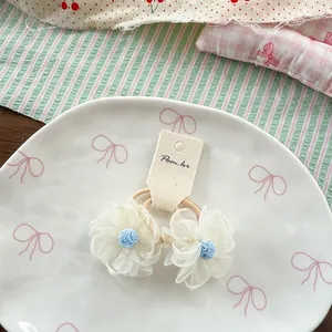 Détail de deux chouchous fleurs en maille blanche avec cœur bleu sur une assiette
