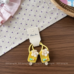 Detail view of yellow knit hair ties with floral embroidery and colorful beads