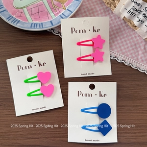 Bunte Stern- und Herz-Haarspangen im Set in Neonpink und Grün auf weißer Kartonkarte