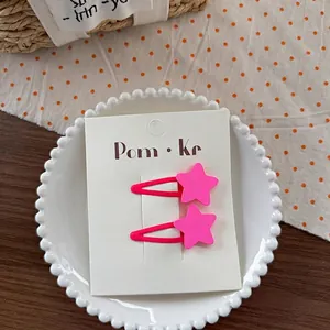Detailaufnahme rosa sternförmiger Haarklammern für Kinder auf einem weißen Teller
