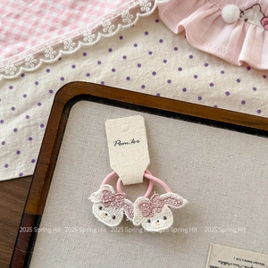 Détail de chouchous roses avec pendentifs de lapin blanc brodés pour enfants