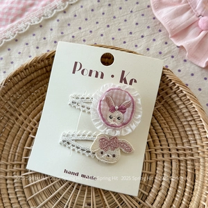 Détail de barrettes lapin brodées à la main sur une carte dans un panier tressé