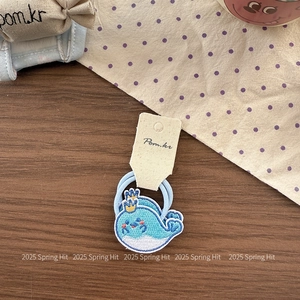 Close-up of cute blue embroidered whale hair tie with gold crown and high-elastic band