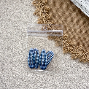 Detail of 4-piece set of blue gingham drop hair clips in transparent packaging