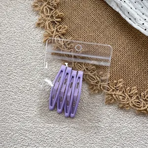 Detailed view of four purple teardrop BB hair clips in a clear retail hanging package