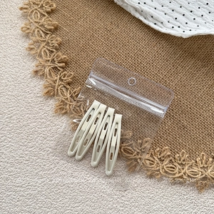 Close-up of four cream matte water drop BB hair clips in transparent OPP packaging