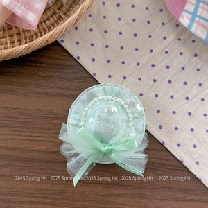 Close-up of a light green sequined mini hat hair accessory with pearls and mesh bow detail
