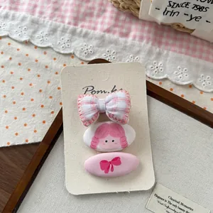 Détail de trois jolies barrettes à carreaux roses sur carte avec nœud et motif fille