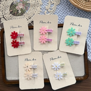 Five sets of daisy floral hair clips in red pink green beige and white on cardboards